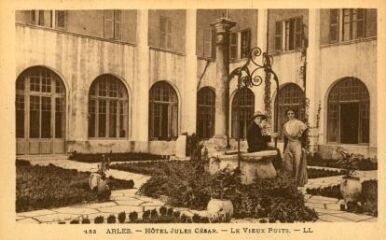 1 vue Arles, Hôtel Jules César, le vieux puits. Vue de la cour avec deux personnages dont une femme en costume arlésien