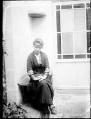 1 vue Portrait d'une jeune femme assise dans une cour intérieure.